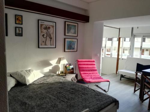 a bedroom with a bed and two pink chairs at Sesimbra Falésia in Sesimbra
