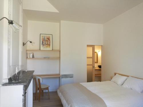 ソレーズにあるGîte Maison de l'Abbéの白いベッドルーム(ベッド1台、デスク付)