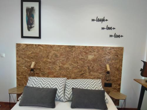 een bed met 2 kussens in een kamer met een bakstenen muur bij Quarto privado Alentejo Litoral in Grândola