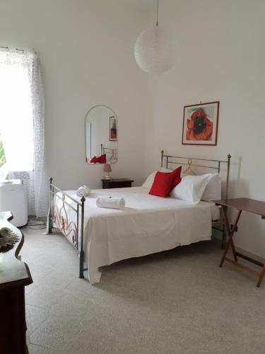 Casa Carolina B&B في سورينتو: غرفة نوم بسرير ذو شراشف بيضاء ومخدات حمراء
