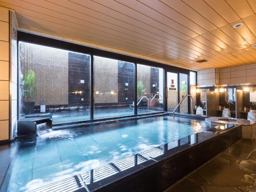 a large swimming pool in a building with a large window at APA Hotel & Resort Nishishinjuku-Gochome-Eki Tower in Tokyo