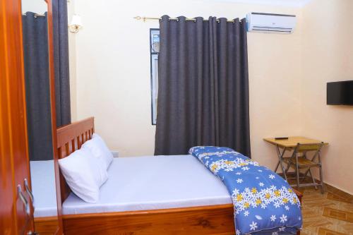 a bedroom with a bed with a blue curtain at Chibuba Airport Accommodation in Dar es Salaam