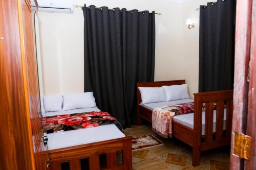 two beds in a room with black curtains at Chibuba Airport Accommodation in Dar es Salaam