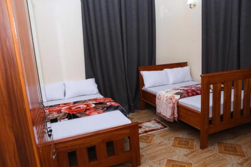 two beds in a room with black curtains at Chibuba Airport Accommodation in Dar es Salaam