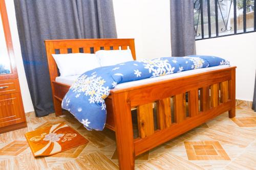 a wooden bed with blue and white pillows on it at Chibuba Airport Accommodation in Dar es Salaam
