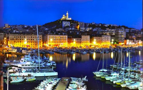 un groupe de bateaux amarrés dans un port la nuit dans l'établissement STUDIO VIEUX-PORT VUE BASILIQUE NOTRE-DAME, à Marseille
