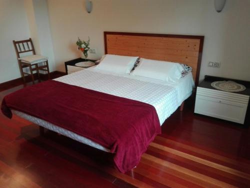a bedroom with a large bed with a wooden headboard at A Casiña de Mera in Santa Marta de Ortigueira