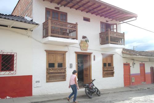 a woman walking past a white building with wooden balconies at Sergeant Pepper's Hostel in Jardin