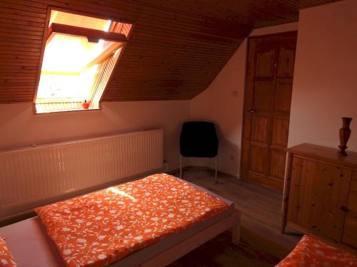 a bedroom with a bed and a window and a chair at Barackos Vendégház Bár in Bár