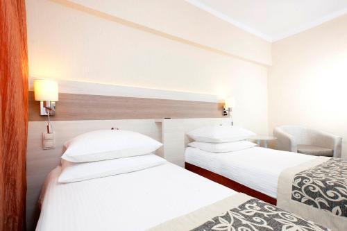 a hotel room with two beds and a chair at Comfort by Trio in Białystok