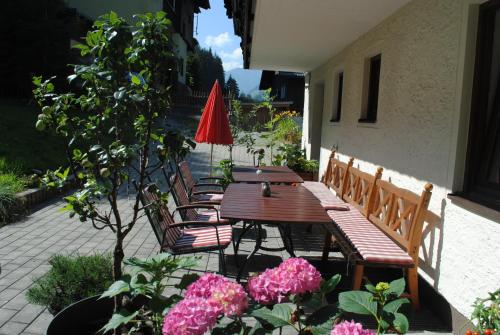 a patio with a wooden table and chairs and flowers at Naturhaus Andrea in Grossarl