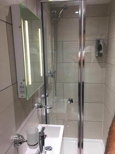 a bathroom with a shower and a sink and a mirror at Crescent Hotel in Reading