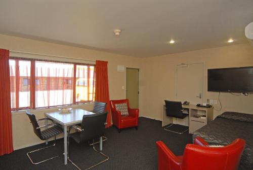 a room with a table and chairs and a tv at Omahu Motor Lodge in Hastings