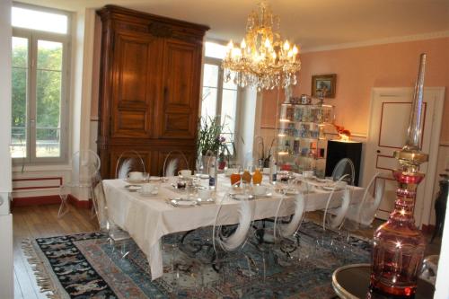 une salle à manger avec une table et un lustre dans l'établissement Relais Du Destin, à Vertrieu