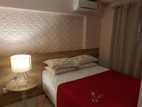 Dormitorio pequeño con cama con manta roja y lámpara en Landscape Beira Mar - 1200 Platinum, en Fortaleza