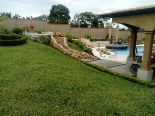 a backyard with a swimming pool and a landscaped yard at Villa El Retiro Luxury Property in Alajuela City