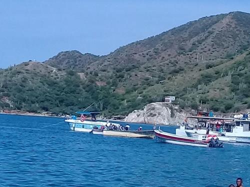 three boats are docked in the water near a mountain at Divijuka in Taganga