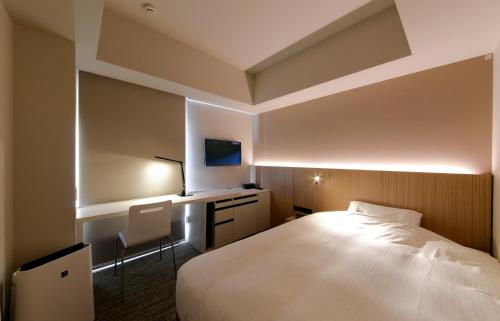 a hotel room with a bed and a desk at JR Inn Sapporo-eki Minami-guchi in Sapporo