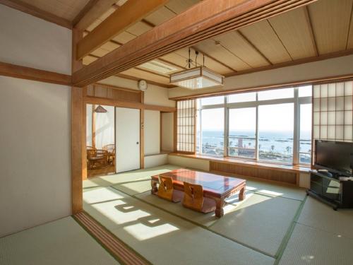 a living room with a table and a large window at Nangoku Hotel in Minamiboso