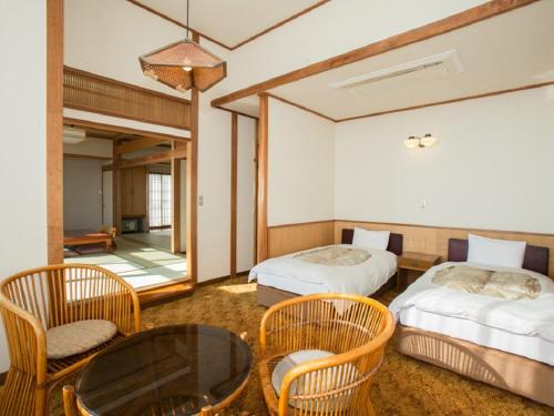a room with two beds and a table and chairs at Nangoku Hotel in Minamiboso