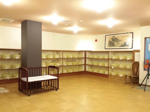 a room with shelves of dishes and a bench at Nangoku Hotel in Minamiboso