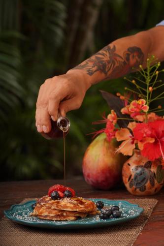 a person holding a spoon over a plate of pancakes at Funky Monkey Lodge in Santa Teresa Beach