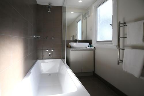 a bathroom with a large white tub and a sink at Leichhardt Cottages in Relbia