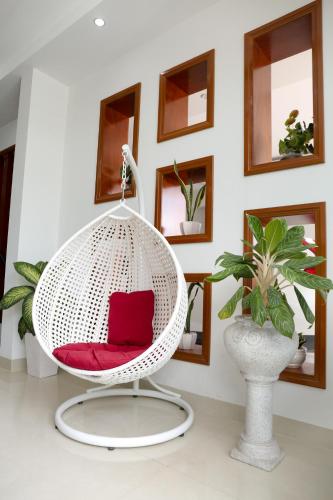 a white wicker chair with a red seat in a room at NAM CẦN THƠ HOTEL in Ấp Phú Thạnh (4)
