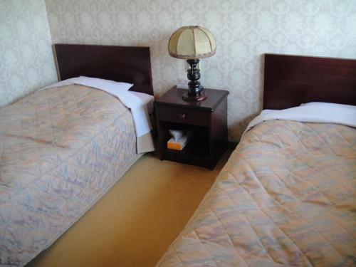 a bedroom with two beds and a lamp on a night stand at Nikko Pension L'escale in Nikko