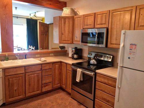 a kitchen with wooden cabinets and a white refrigerator at Right on Main St Hot Tub Close to Marina Garage in Frisco