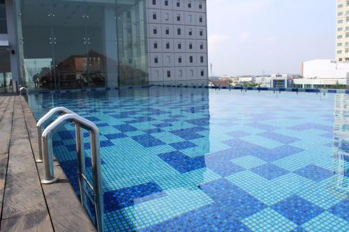 una piscina con azulejos azules en la parte lateral de un edificio en HARRIS Hotel & Conventions Solo en Solo