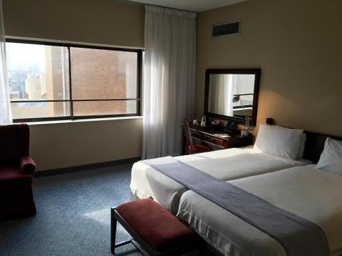 a hotel room with a bed and a desk and a window at The Royal Hotel by Coastlands Hotels & Resorts in Durban