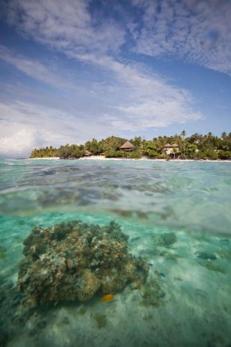 a reef in the ocean with an island in the background at Pacific Resort Aitutaki - Adults Only in Arutanga