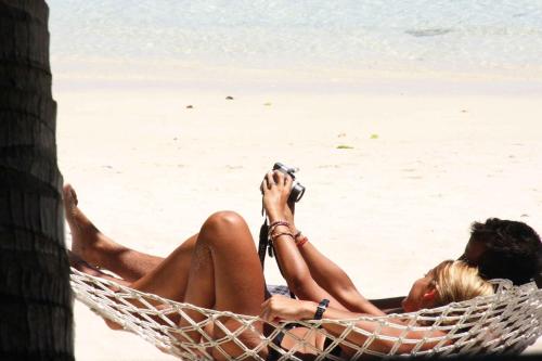 two people laying in a hammock on the beach at Pacific Resort Aitutaki - Adults Only in Arutanga