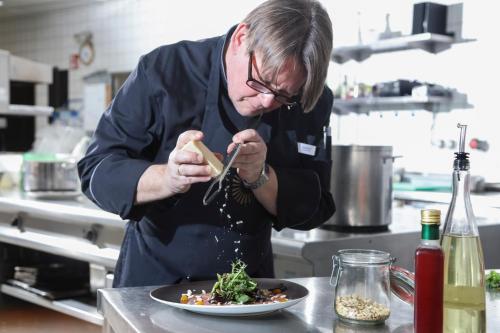 a man in a kitchen preparing a plate of food at Schwarzwald Panorama in Bad Herrenalb