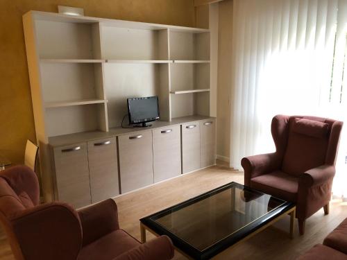 ein Wohnzimmer mit einem Sofa, 2 Stühlen und einem TV in der Unterkunft Apartamentos Villava Pamplona in Villava