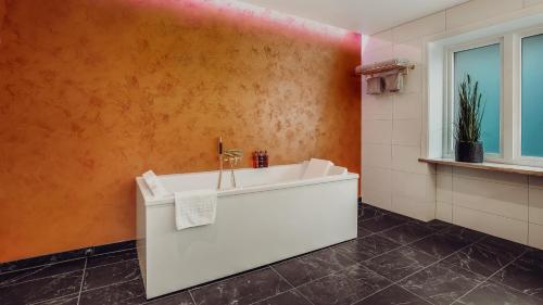 a bathroom with a white tub and an orange wall at Home Hotel Grand Bodø in Bodø