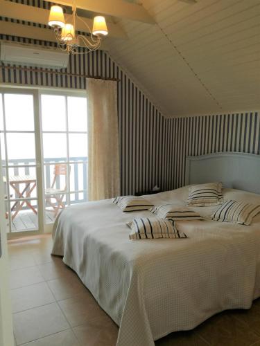 a bedroom with a white bed with a balcony at Namelis prie marių in Nida