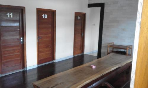 a room with three wooden doors and a wooden table at Tanjung Inn in Wonosari
