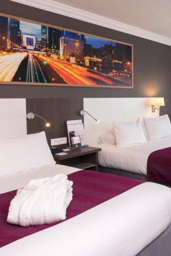 two beds in a hotel room with a picture on the wall at Best Western Plus Paris Orly Airport in Rungis
