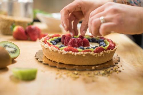 iemand die bessen op een fruittaart op een tafel legt bij Hotel La Perla Rimini in Rimini