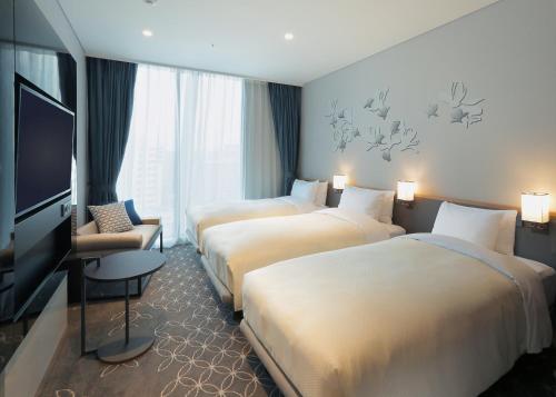 a hotel room with three beds and a flat screen tv at Hotel Gracery Seoul in Seoul