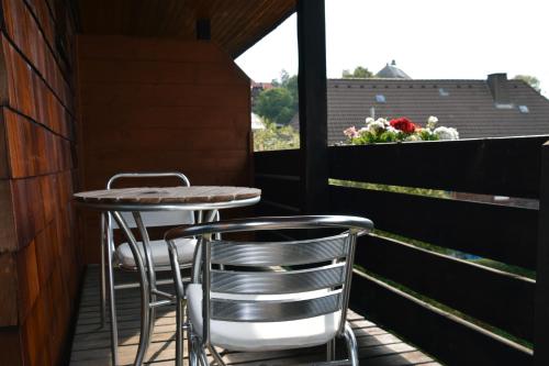 balcón con 2 sillas, mesa y ventana en Pension am See, en Schluchsee