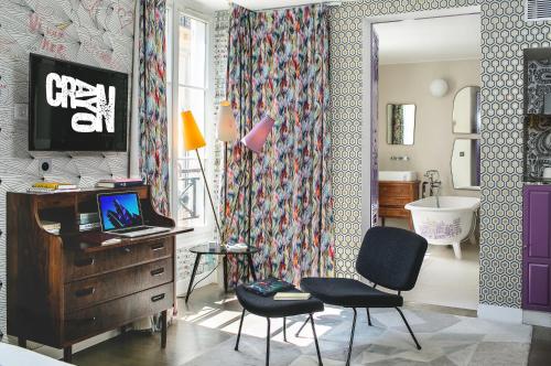 a living room with a chair and a desk at Hôtel Crayon by Elegancia in Paris