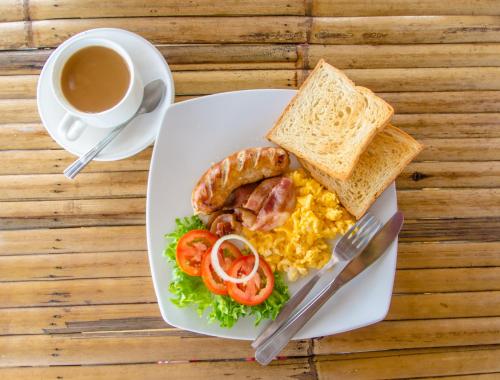 a plate of eggs bacon sausage and toast and a cup of coffee at Haad Son Resort (Koh Raham) in Haad Son