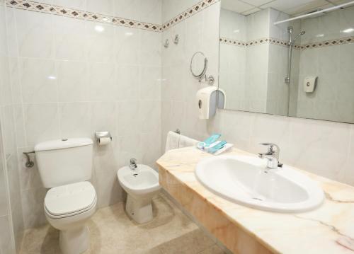 a bathroom with a white toilet and a sink at KAKTUS Hotel Volga - Adults Recommended in Calella