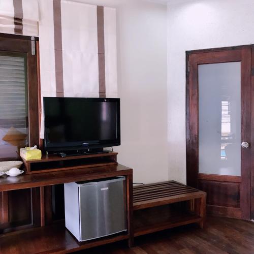 a flat screen tv sitting on a wooden stand next to a door at Ancient Luangprabang Hotel in Luang Prabang