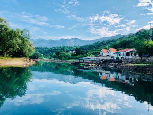 a river with reflections of buildings in the water at Splav "Slap" - Bungalovi in Danilovgrad