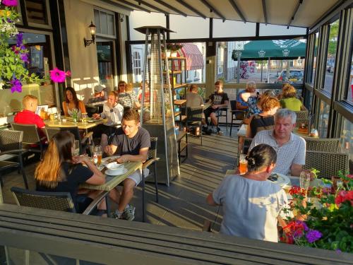 een groep mensen die aan tafel zitten in een restaurant bij Hotel Café Restaurant "De Kroon" in Wissenkerke