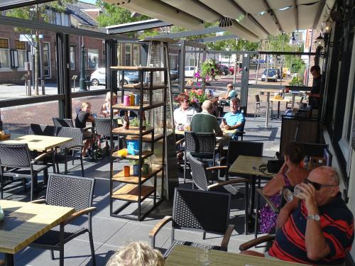 een groep mensen die aan tafel zitten in een restaurant bij Hotel Café Restaurant "De Kroon" in Wissenkerke